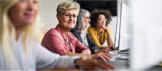 mulheres reunidas em frente a computadores